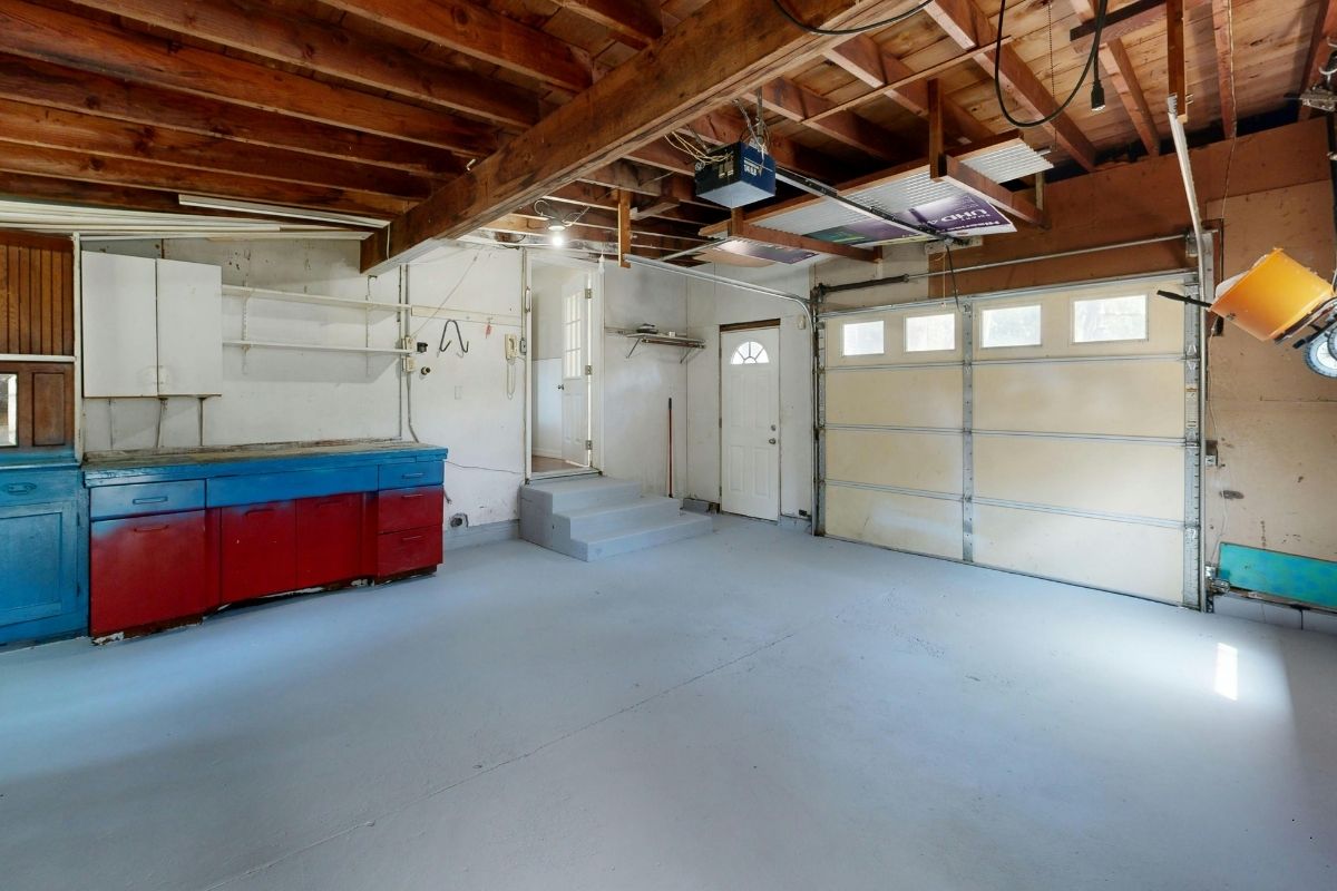 Empty two-car garage with exposed rafters and workbench before conversion in a Florida home