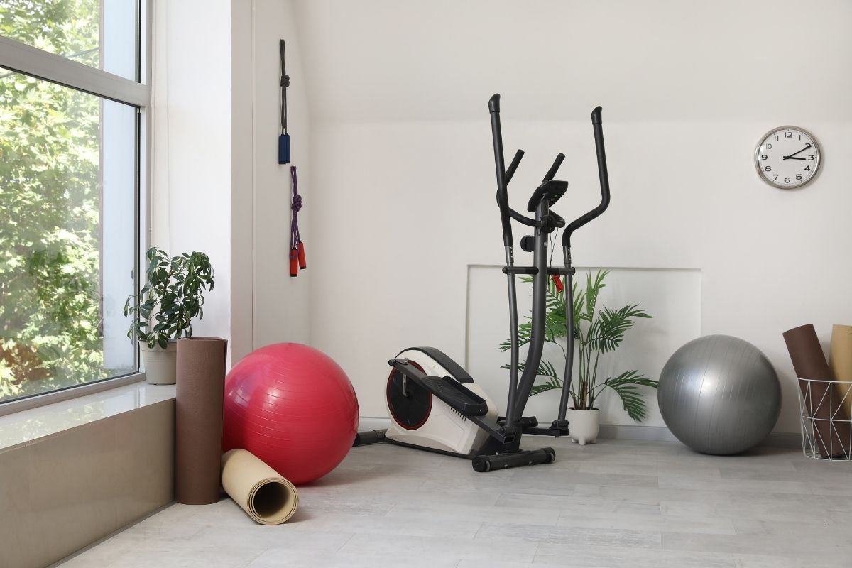 Garage converted to a home gym with elliptical machine, exercise balls, yoga mat, and plants